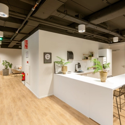 Modern office space in Hilversum with a furnished kitchen area featuring a bar counter and stools, ideal for office space rental or an office to rent.