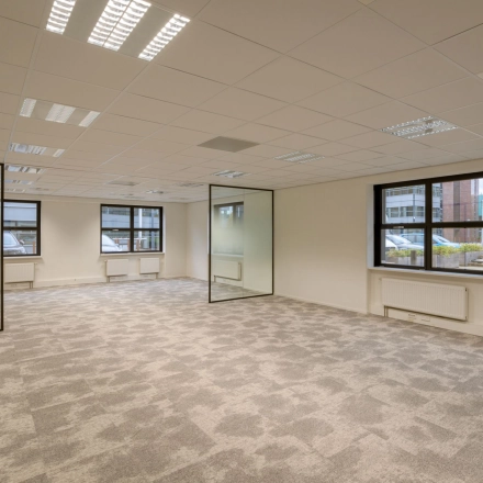 Spacious office space to rent at Olympia 1, Hilversum, featuring large windows and carpeted flooring.