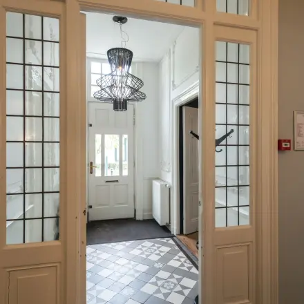 Entrance area at Oude Enghweg 8 in Hilversum, featuring stylish flooring and a modern chandelier, ideal for an office space rental.