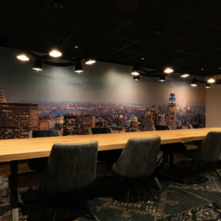 Modern conference room at Steijnlaan 16, Hilversum, featuring a large wooden table and cityscape wall mural, ideal for office space rental.