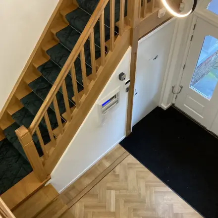 Interior view of office entryway at Utrechtseweg 47, Hilversum, featuring wooden stairs and parquet flooring, suitable for office space rental.
