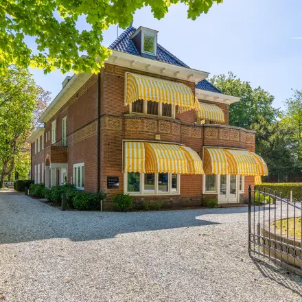 Exterior view of an office space rental at Utrechtseweg 47, Hilversum with a brick facade and striped awnings.