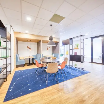 Bright office space for rent at Polarisavenue 130-150, Hoofddorp with modern furnishings including a round table, chairs, and decorative shelving, ideal for casual meetings.