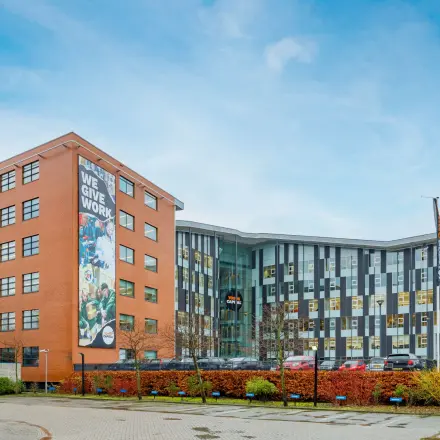 Exterior view of Siriusdreef 16 in Hoofddorp, featuring a modern office building with parking facilities. Ideal office space rental opportunity in a vibrant business environment.