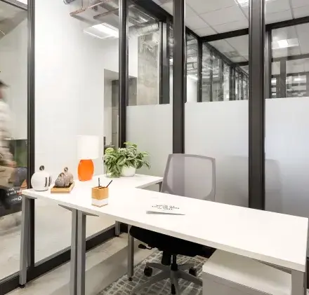 Modern office space at Siriusdreef 17, Hoofddorp with sleek furnishings and glass partitions, ideal for rent office space enthusiasts. A person is walking past, adding a dynamic touch to the office environment.