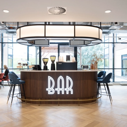 Spacious lounge area at Siriusdreef 60, Hoofddorp, featuring a modern bar with stylish seating and large windows. Ideal for office space rental with relaxed communal vibes.