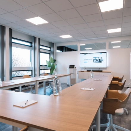Modern office space rental in Hoogeveen with furnished conference room at De Vos van Steenwijklaan 75, featuring large windows, ample seating, and a presentation setup.