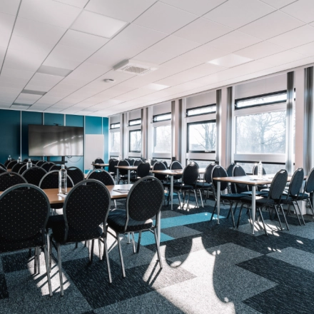 Bright office space rental at De Vos van Steenwijklaan 75 in Hoogeveen, featuring rows of chairs and tables ideal for meetings or conferences.