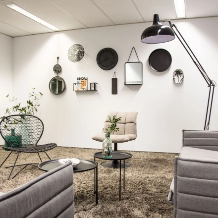 Furnished office space for rent featuring stylish gray sofas, a standing lamp, and decorative wall items, located at Meidoornkade 22, Houten.