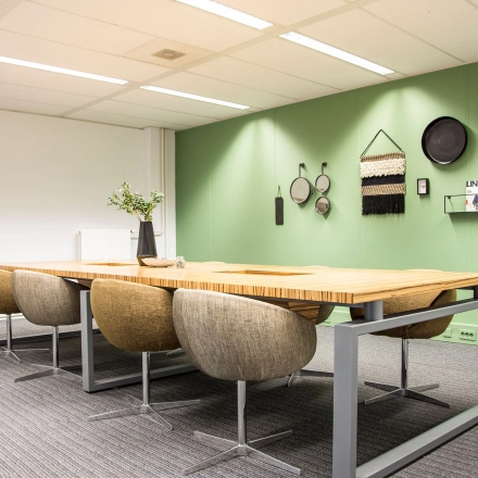 Modern office to rent at Meidoornkade 22, Houten, featuring a stylish meeting area with a wooden table and comfortable chairs, suitable for office space rental.