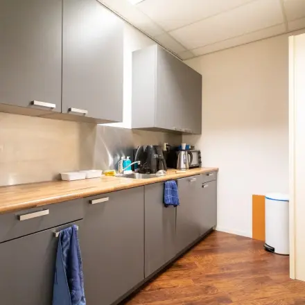 Cozy pantry space at Sandtlaan 36, Katwijk, equipped with storage cabinets, a coffee maker, and a dishwasher, perfect for office space rental.
