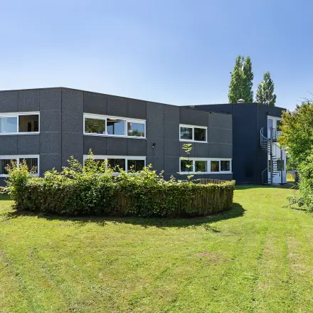 Exterior view of office building at Ouddeelstraat 7a, Leeuwarden, with lush green surroundings, available for office space rental.