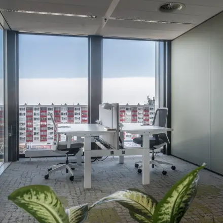 Modern office space rental at Bargelaan 200, Leiden, featuring large windows and two desks with chairs, overlooking the cityscape.