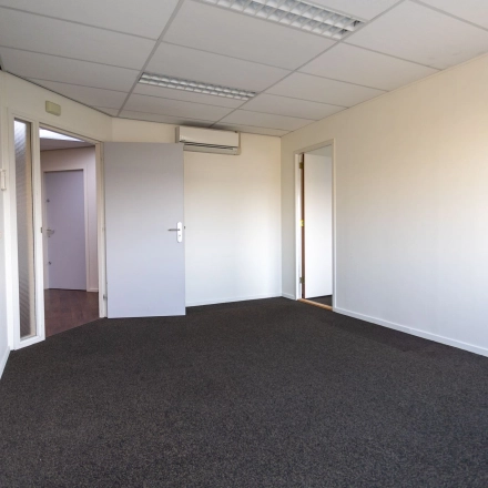 Interior view of unfurnished office space available for rent at Fruitweg 22, Leiden, featuring a carpeted floor and overhead lighting.