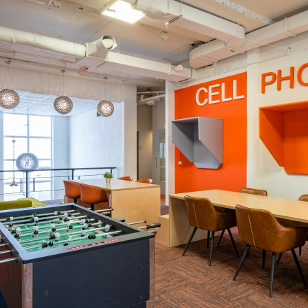Modern interior office space at Touwbaan 38, Leiderdorp, featuring a vibrant lounge area with a foosball table, seating, and phone booths. Available for office space rental in a lively setting.