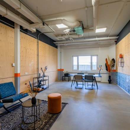 Office space rental at Touwbaan 38 in Leiderdorp featuring a modern interior with blue chairs, tables, and decorative elements, perfect for casual meetings or work sessions.