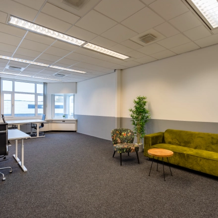 Spacious office to rent at Touwbaan 38, Leiderdorp, featuring a bright area with a green sofa, floral chair, and modern desks for office space rental.