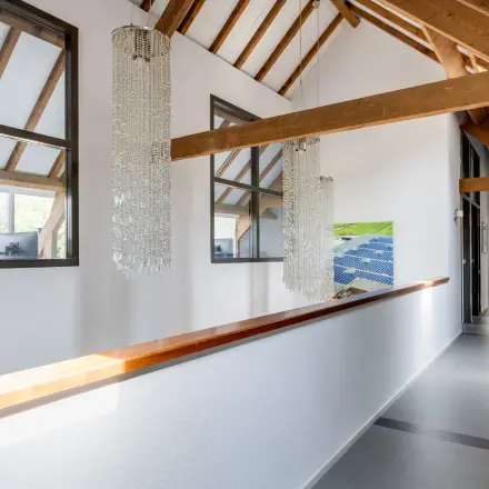 Bright office corridor with wooden beams and chandeliers at Hamersveldseweg 120, Leusden, available for office space rental.