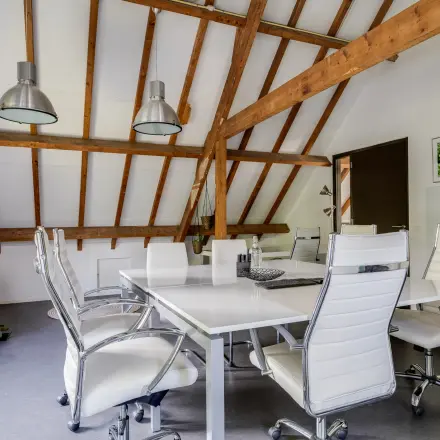 Modern office with exposed beams and sleek furnishings at Hamersveldseweg 120, Leusden, available for office space rental. Spacious seating setup for collaborative meetings.