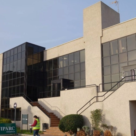 Modern office building at Calle de la Azalea 1, Madrid Alcobendas, featuring large glass windows ideal for office space rental. Individuals are seen walking outside, highlighting an office to rent.