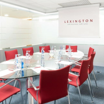 Bright modern conference room with red chairs and a glass table set for a meeting, ideal for office space rental in Madrid Alcobendas.