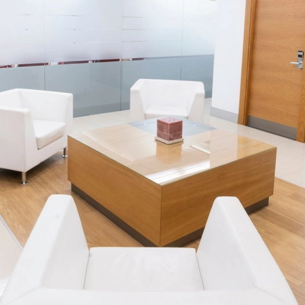 Modern office lounge at Calle de la Caléndula 93, Madrid Alcobendas, featuring sleek white chairs and a wooden table. Ideal office to rent for meetings or casual discussions.