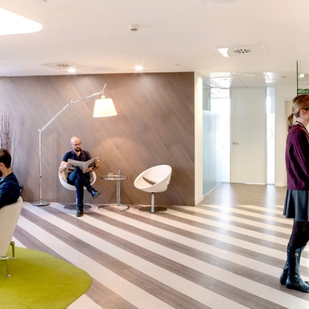 Bright and modern office space at Paseo de la Castellana 141, Madrid Azca, featuring a reception area with people collaborating. Ideal for office space rental with a stylish and functional design.