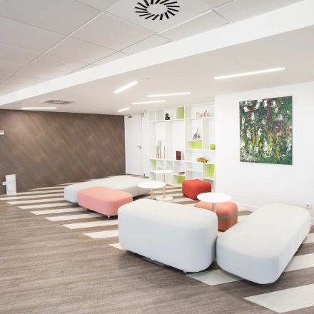 Open and inviting office area with modern seating and decorative shelving, located at Paseo de la Castellana 141, ideal for office space rental in Madrid Azca.