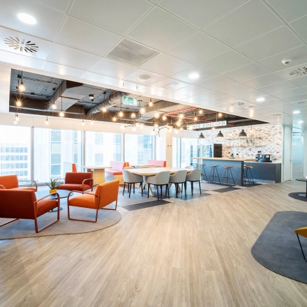 Bright, modern office space with colorful seating areas and panoramic windows, located at Paseo de la Castellana 79, ideal for rent office space in Madrid Azca.