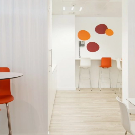 Bright, furnished office space at Paseo de la Castellana 79 in Madrid Azca with colorful seating and wall decor, ideal for office space rental.
