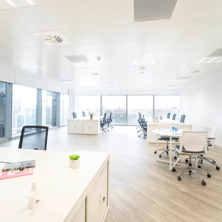 Bright and spacious office to rent in Madrid Azca with desks and chairs, featuring large windows for natural light.