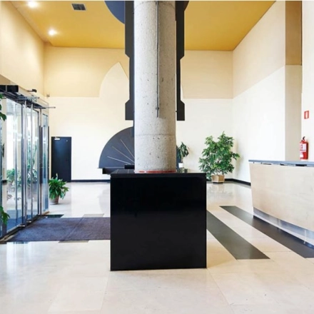 Spacious office entrance at Avenida de Aragón 334, Madrid Barajas, featuring a sleek reception desk and lush plants, ideal for office space rental.