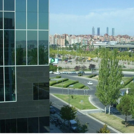 View of the modern office building's exterior with surrounding cityscape at Avenida del Partenón 16-18, ideal for office space rental in Madrid Barajas.