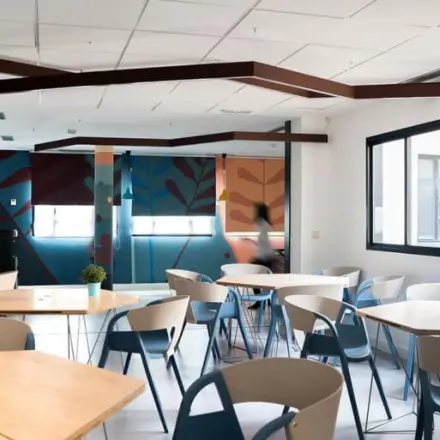 Bright office to rent in Madrid Center with modern furnishings, featuring colorful elements and ample seating, ideal for collaborative work or meetings.