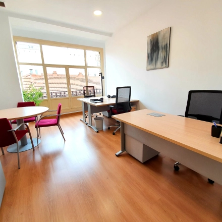 Bright office space with large windows, modern furniture, and two desks at Calle Gran Vía 6, perfect for rent office space in Madrid Center.