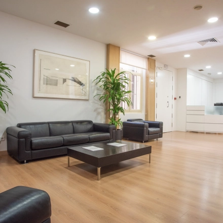 Spacious office lounge at Calle Gran Vía 6, Madrid Center, featuring leather sofas and modern decor. Ideal office space rental for relaxation and informal meetings.