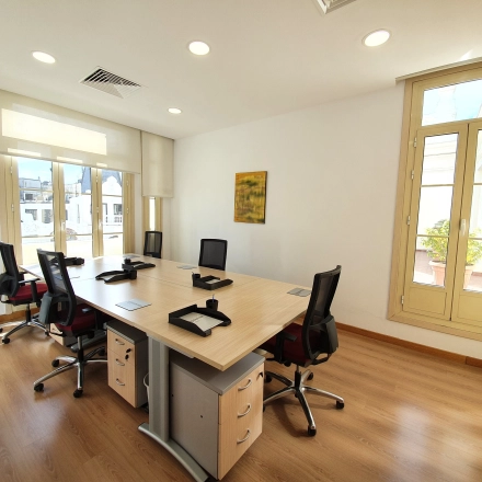 Bright office space for rent at Calle Gran Vía 6, Madrid Center, featuring large windows, desks, and chairs, perfect for office space rental.