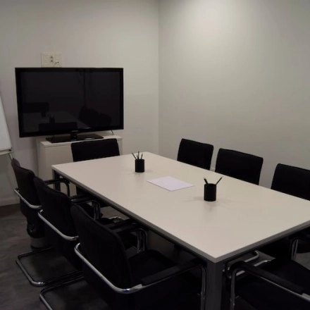 Modern conference room for office space rental at Plaza Santa María Soledad Torres Acosta 1, Madrid Center, featuring a large table, chairs, a whiteboard, and mounted screen.