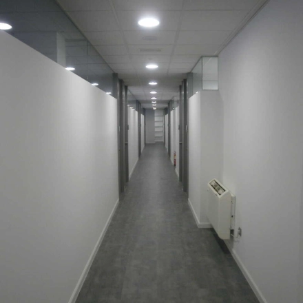 Long corridor in an office building at Plaza Santa María Soledad Torres Acosta 1, in Madrid Center, ideal for office space rental. Bright, with clean lines and modern lighting suitable for professional use.