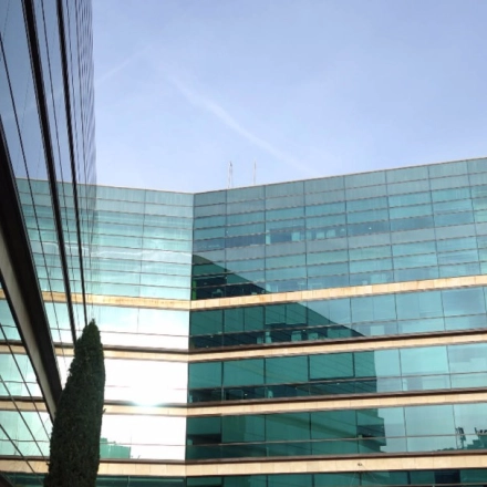 Modern glass office building with reflective surfaces in Madrid Hortaleza, ideal for office space rental.