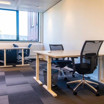 A furnished office space at Paseo de Recoletos 5, Madrid Recoletos, featuring desks and chairs, ideal for rental. The office to rent is well-lit with large windows.