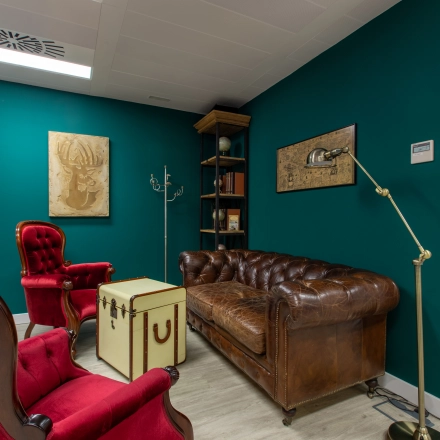 Cozy office space with vintage leather couch, red armchairs, and decor, ideal for office space rental on calle de O'Donnell, Madrid Retiro.