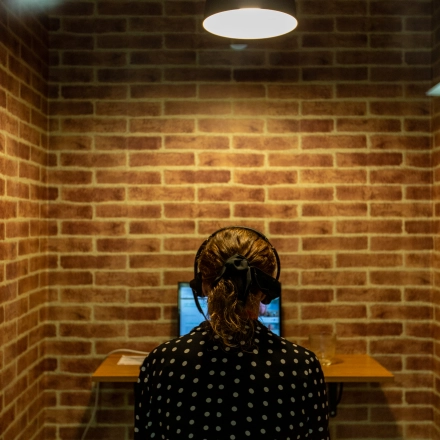 An individual working on a laptop in a brick-walled office space, ideal for those seeking office space rental at calle de O'Donnell, Madrid Retiro.