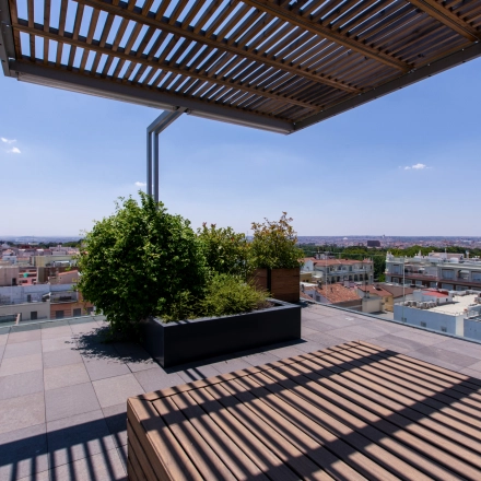 Roof terrace view at an office to rent on calle de O'Donnell, Madrid Retiro, featuring a wooden pergola and cityscape.