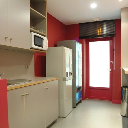 Compact office pantry with red walls, equipped with a microwave, mini fridge, and vending machine for efficient office space rental.