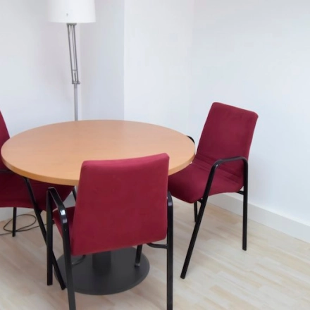 Cozy office space rental at Calle Capitan Haya 60 in Madrid Tetuán, featuring a small round table with red chairs, perfect for meetings.