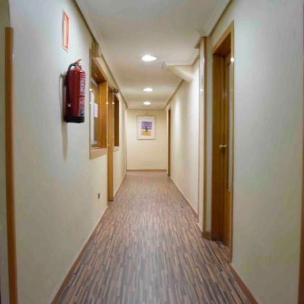 A long, well-lit corridor with wooden doors, located in an office to rent at Calle Capitan Haya 60, Madrid Tetuán.