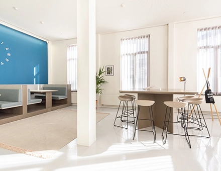 Bright office space at Kardinaal Mercierplein 2 featuring modern furnishings, booths, and a meeting table, ideal for office space rental in Mechelen Centrum.
