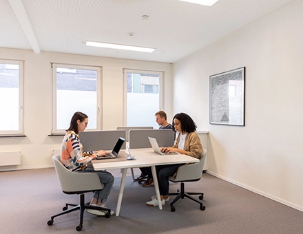 Modern office space rental in Mechelen Centrum with people working on laptops at Kardinaal Mercierplein 2, featuring natural light and stylish furniture.