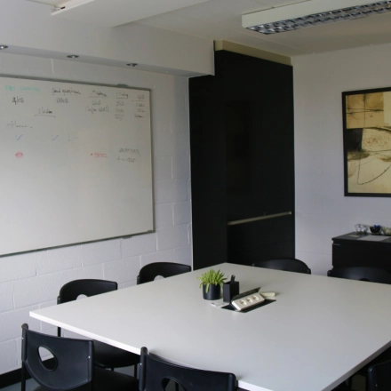 A bright conference room at De Regenboog 11, Mechelen North, featuring a large whiteboard and a modern table. Ideal for an office space rental.